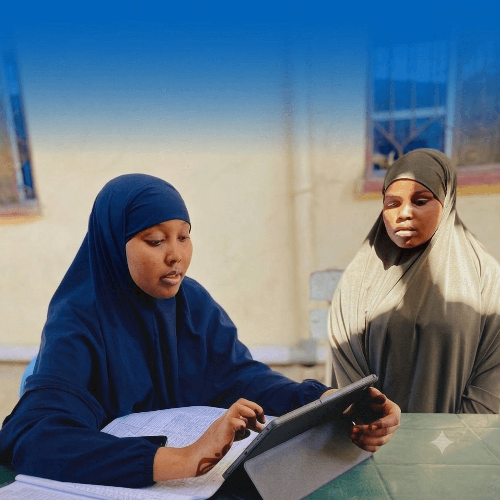 Community health workers using a digital tablet alongside a paper health register
